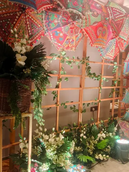 A Navratri-themed photo corner. We used a wooden trellis decorated with colorful embroidered umbrellas and floral arrangements to create a perfect spot for festive pictures.