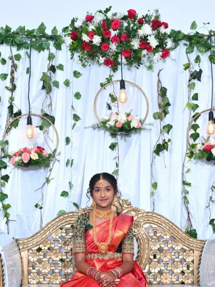 A young girl celebrating her half-saree function. The backdrop is a modern design with a white curtain, hanging floral hoops, and Edison bulbs for a touch of elegance.