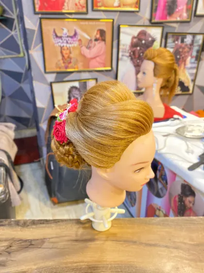 A side view of the student's work, highlighting the smooth puff at the front and the secure placement of the bun.