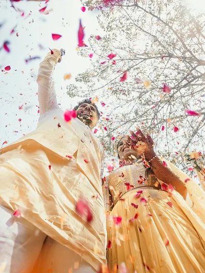 Looking up at the happy couple as they are showered with petals, a beautiful and dynamic shot that captures the festive spirit of the Haldi.
