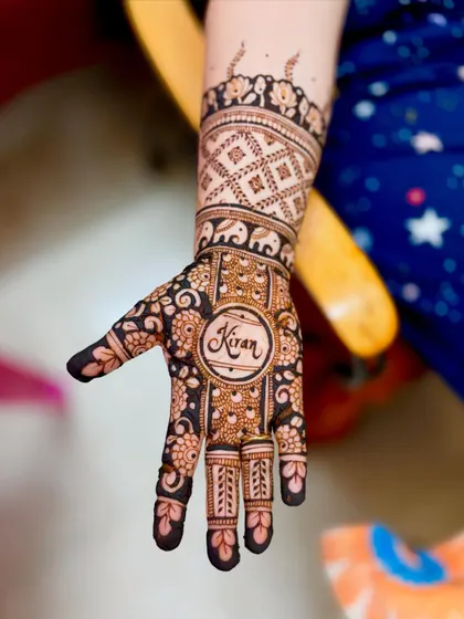 A close-up of the personalized element in Shubha's mehendi, featuring her son's name, "Kiran."