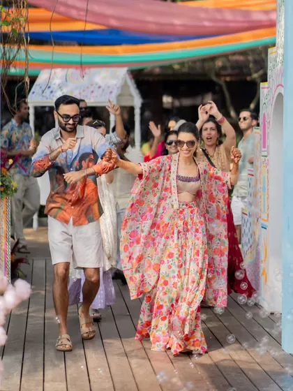 The couple making a fun and energetic entrance to their Haldi party in Goa, surrounded by friends and bubbles.