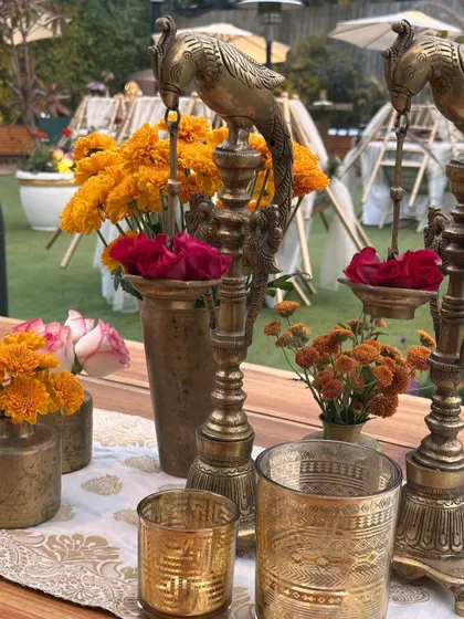 A table centerpiece combining brass peacocks, marigolds, and roses, showcasing our attention to detailed, thematic decor.
