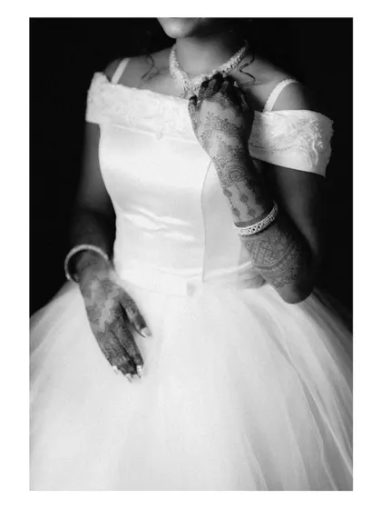 A black and white photo of a Christian bride in her beautiful white gown, her henna-adorned hands a lovely fusion of traditions.