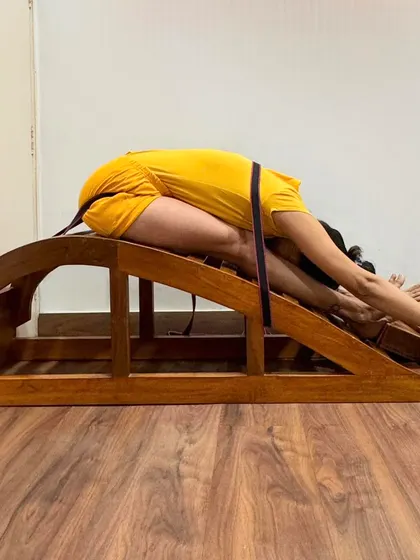 Using a backbend bench and belt for Janu Sirsasana (Head-to-Knee Pose) allows for a deep, supported forward bend. The belt helps to extend the spine, while the bench supports the torso, preventing strain.