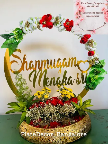 This is a personalized ring platter I designed for an engagement. It features the couple's names in a beautiful golden script, surrounded by fresh flowers, making the moment even more special.