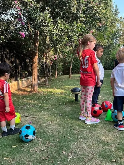 A group of children listens intently to their coach before a drill. This moment highlights the importance of focus and discipline, which we teach alongside football skills.