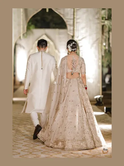 A shot of the couple from behind, highlighting the bride's beautiful lehenga and hairstyle.