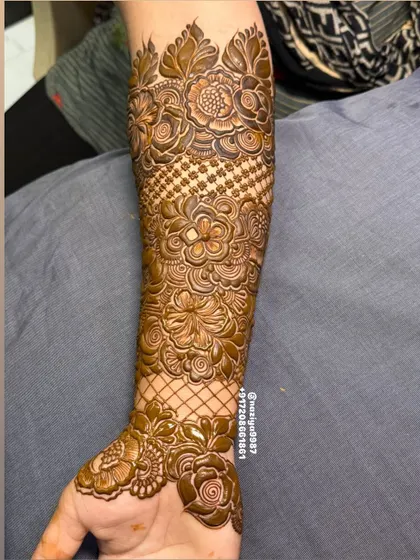 This arm design combines floral patterns with classic net or 'jaali' work. The criss-cross pattern adds a beautiful texture to the overall mehandi.