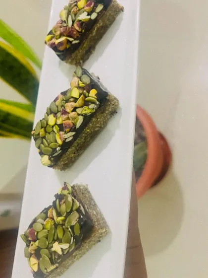 These are my Pumpkin Seed & Fig nutritional bars, topped with rich vegan chocolate and a generous sprinkle of pistachios. They are the ideal on-the-go snack, providing sustained energy without any refined sugar.