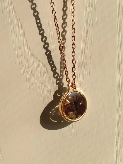 This is another look at the rose gold pendant with preserved rose petals. The simple chain and classic round shape make it a versatile accessory that can be worn with any outfit.