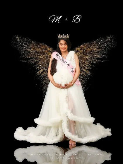 An angelic portrait with sparkling, golden wings against a black background. The "Mom to be" sash adds a celebratory touch to this fantasy-themed maternity shoot.