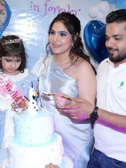 A family celebrates with a Frozen-themed cake featuring an Olaf figurine.