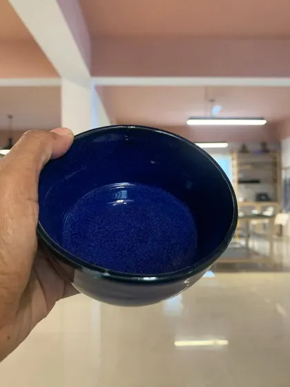 A student's wheel-thrown bowl with a stunning, deep blue speckled glaze. The glossy finish and rich color are absolutely mesmerizing.