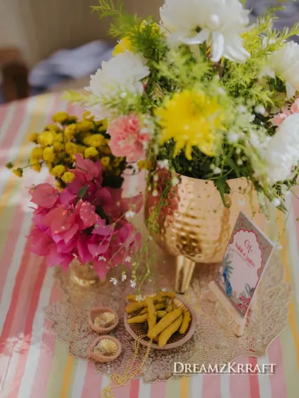 A small, thoughtful detail from the Haldi ceremony: a tray with turmeric sticks, diyas, and a personalized card, all beautifully arranged with fresh flowers.
