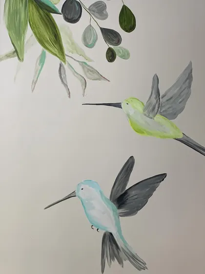 A detail from a bedroom mural featuring soft, pastel-colored hummingbirds. This kind of artwork adds a touch of delicate movement and nature to a personal space.
