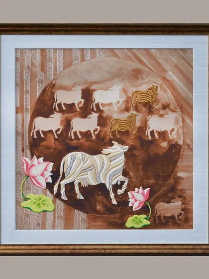 A studio shot of a finished and framed piece from the Nandi Collection. The composition features a herd of sacred cows within a circular motif, a common element in traditional Indian art.