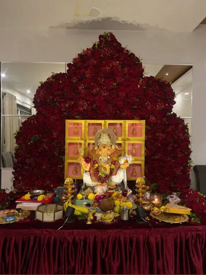 A truly magnificent and devotional setup, this backdrop is shaped like a temple or throne and constructed from thousands of red roses.