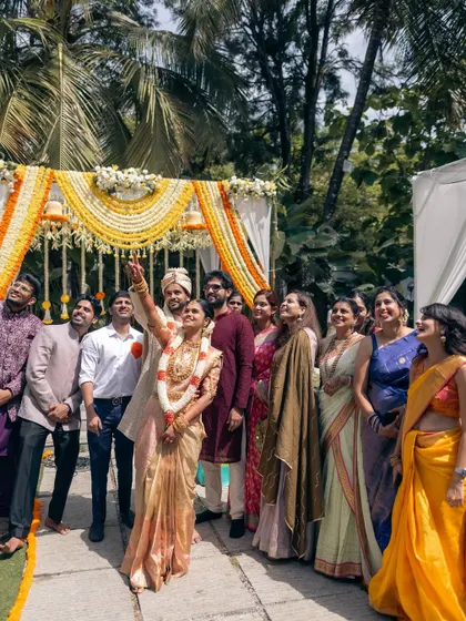 A joyous moment with family and friends right after the ceremony. The outdoor mandap, decorated with yellow and white florals, provides a bright and cheerful backdrop for group photos.