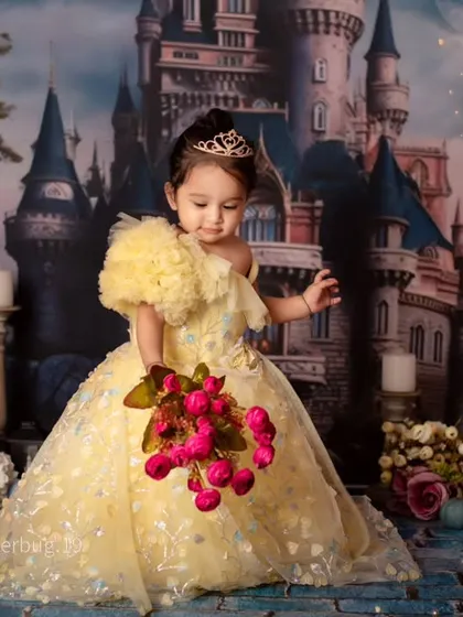 Our little princess holds a bouquet of flowers, looking enchanting in front of her very own castle.