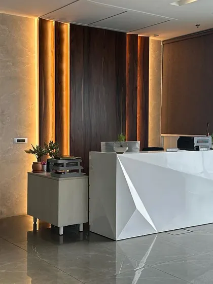 A side view of the reception desk, showing its angular form and the interplay of light and shadow from the vertical wall lighting.