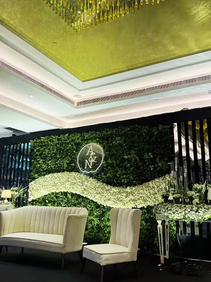A wider angle of the green wall stage, showing how it integrates with the venue's architecture and overhead lighting to create a sophisticated focal point.