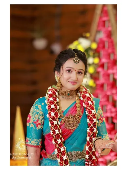 Dr. Vishnu Priya adorned with a flower garland. Her makeup is soft and radiant, a perfect example of a timeless South Indian bridal look.
