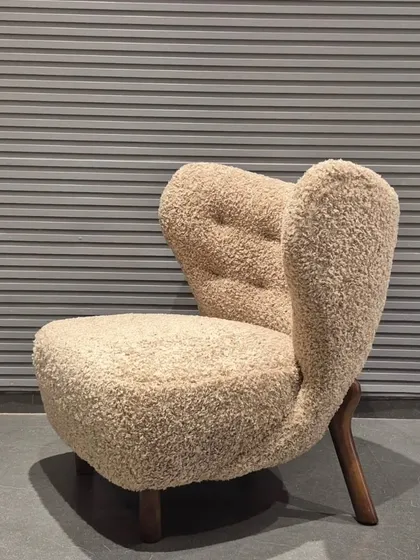 This is one of my favourite designs, a lounge chair upholstered in a beautiful bouclé fabric. The unique, sculptural form and solid wood legs make it a true statement piece for any living room or building lobby.