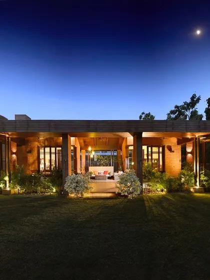 At night, the K Pavilion becomes a warm, inviting outdoor living room. The wooden structure is illuminated to highlight its form, creating a perfect space for evening relaxation that overlooks the garden.