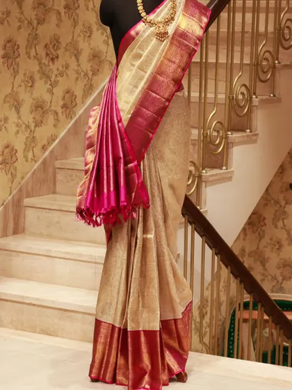 A tissue Kanjivaram in gold with a striking pink border and pallu, styled on a mannequin to showcase its grand and flowing drape.