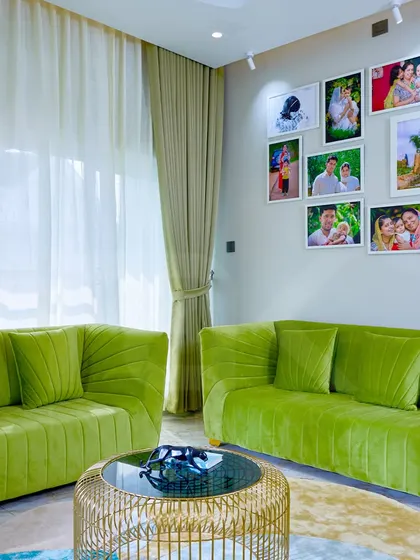 A cozy and elegant family living area, featuring vibrant green sofas that add a burst of energy. The gallery wall of family photos makes the space deeply personal and full of memories.