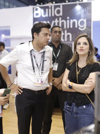 Sussanne Khan and an exhibitor discuss the finer points of a smart home product, highlighting the detailed conversations that drive product adoption.