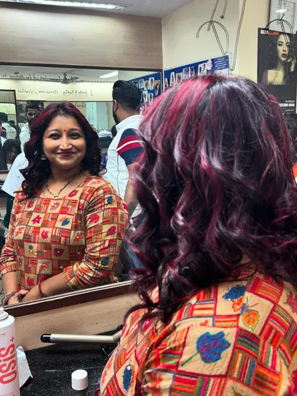 A happy client admiring her new red hair color and bouncy curls in the mirror. Our goal is to teach students how to make their clients feel confident and beautiful.