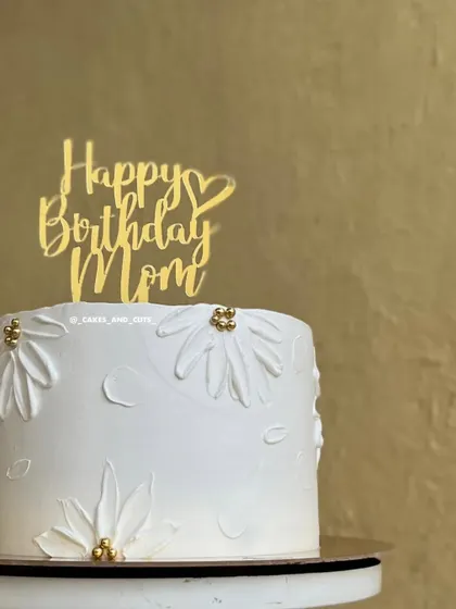 A lovely cake for a mom, decorated with piped daisies and a "Happy Birthday Mom" topper. Simple piping can create beautiful floral textures.