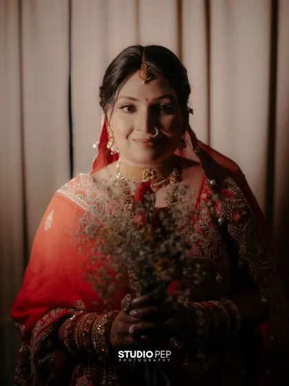 A warm, intimate portrait of the bride, Shalini, holding a bouquet of flowers, her smile genuine and full of joy.