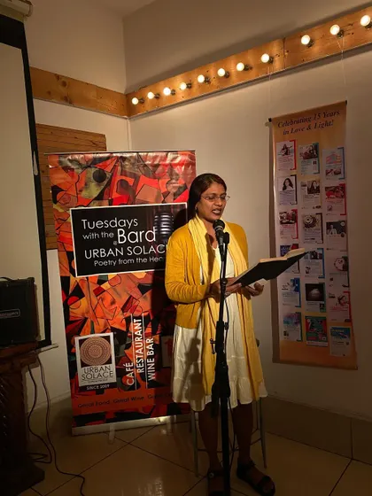 A performer shares her poetry, her expression lit by the warm stage lights. Every Tuesday, our cafe transforms into a sanctuary for words.