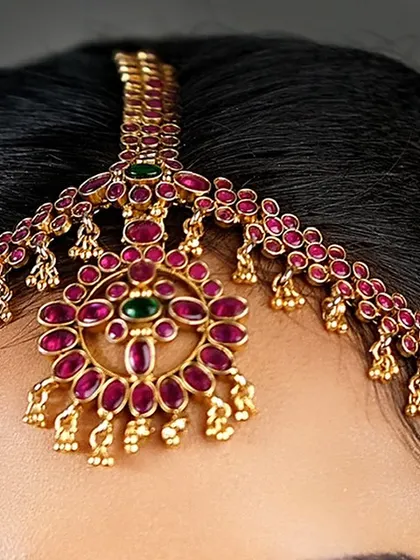 A detailed close-up of the traditional matha patti. This type of head jewellery is a key element of the South Indian bridal look.