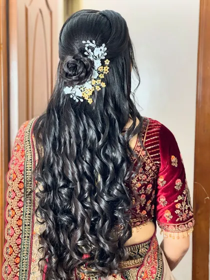 A beautiful half-up, half-down hairstyle with long, flowing curls. This romantic style is perfect for a reception or sangeet and is finished with a pretty floral hair accessory.