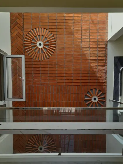 A straight-on view of the brick feature wall in the central courtyard. The circular patterns and herringbone layout create a dynamic texture that plays beautifully with the shadows cast by the skylight above.