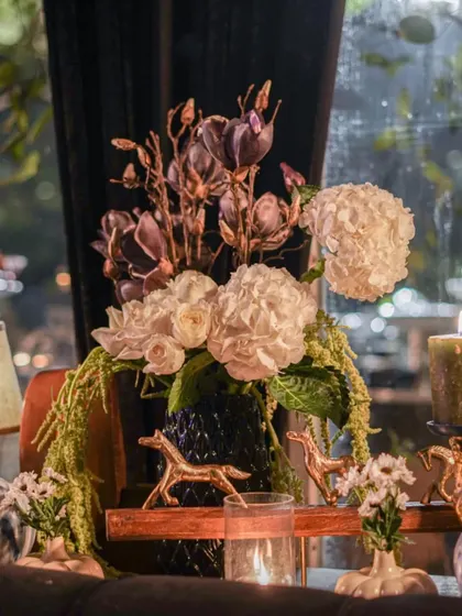 An arrangement featuring white hydrangeas and rare, dark purple magnolia blooms. The contrast creates a moody and artistic floral statement, perfect for a sophisticated evening event.