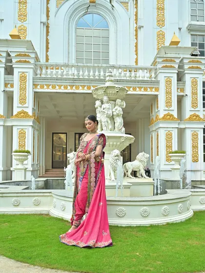 A full-length view of a modern Maharashtrian bride in a pink Nauvari, set against a grand, royal backdrop.