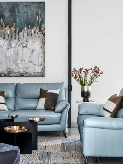Another angle of the living room, highlighting the hero powder blue sofa and custom color-blocked cushions. The abstract painting adds depth, while the black and gold coffee table ties into the room's architectural details.