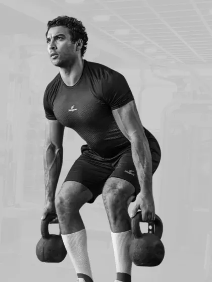 A man demonstrates his strength with a double kettlebell deadlift, a powerful exercise for building the posterior chain.