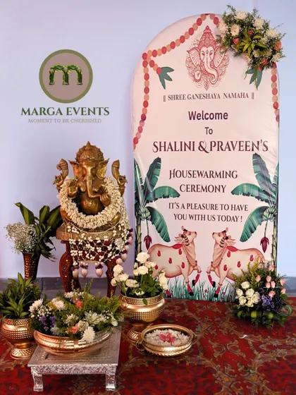For this Gruhapravesham, I created a welcoming entrance that blends tradition with personal touches. The setup features a sacred Ganesha idol, fresh flower arrangements in brass urlis, and a custom banner to welcome Shalini and Praveen to their new home.