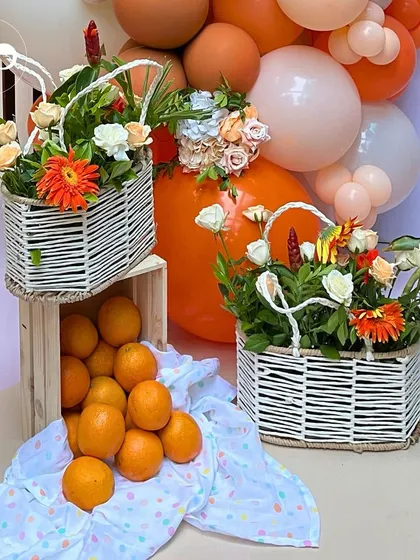 Baskets of fresh oranges and floral arrangements add to the rustic charm of this citrus themed decor. The combination of natural fruit, flowers, and woven baskets creates a wholesome and inviting atmosphere.