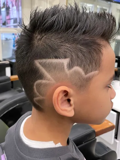 Rocking that sharp edge and fresh fade. This young client is showing off his cool new haircut with a creative design.