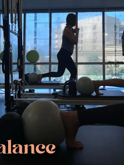 It's all about balance. This shot captures a client performing a challenging lunge variation on the reformer, using a Pilates ball for added instability to engage the core.