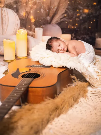 Another angle from our musician-themed newborn shoot. The baby is sleeping on a soft rug, right next to the guitar, creating a beautiful composition.
