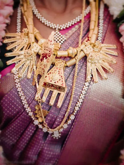 A detailed shot of a unique and traditional gold necklace worn by the bride. This close up allows you to appreciate the intricate design and cultural significance of the wedding jewelry.