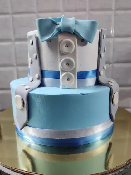 A "little man" themed two-tier cake. This adorable design features a shirt with a bow tie and suspenders, perfect for a first birthday.